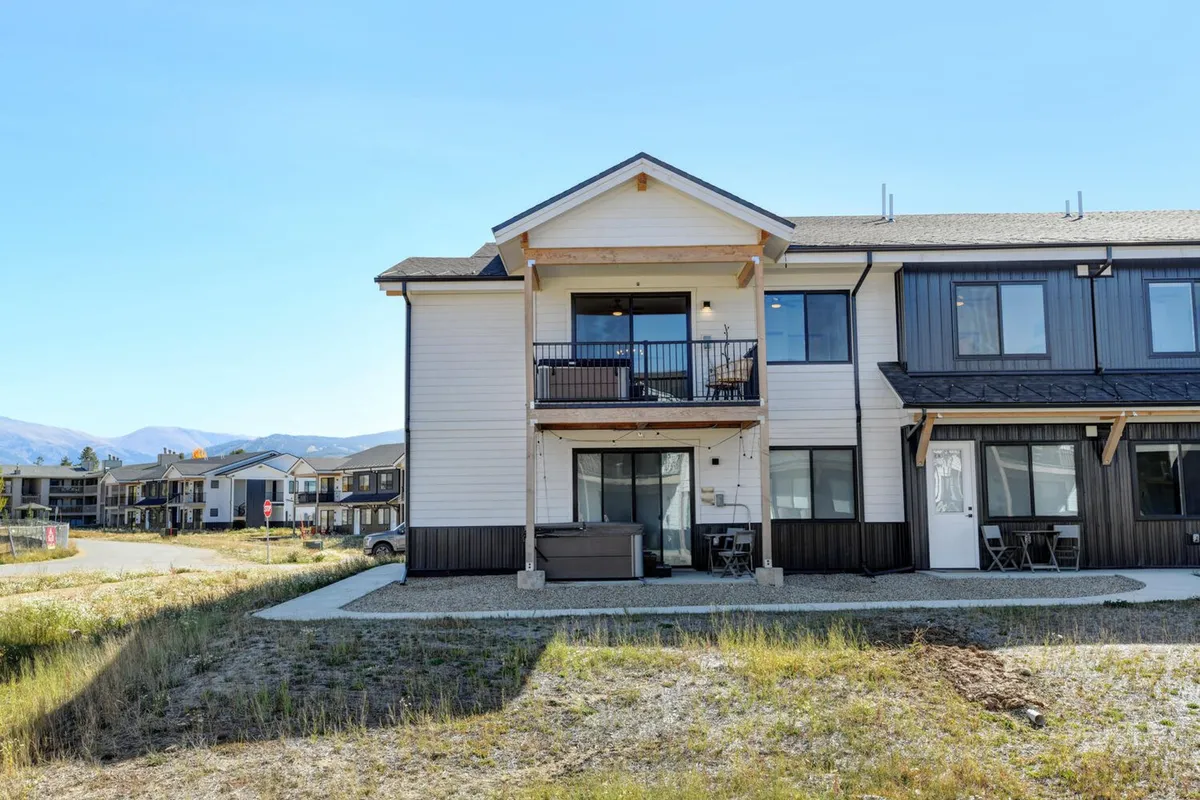 A welcoming modern condo exterior featuring a balcony and expansive windows. The balcony provides an inviting spot for relaxation or gathering, while large windows hint at bright, airy interiors and a seamless connection between indoor comfort and outdoor scenery. The image exudes a sense of sophistication and hospitality, with the surrounding area suggesting community and leisure opportunities.
