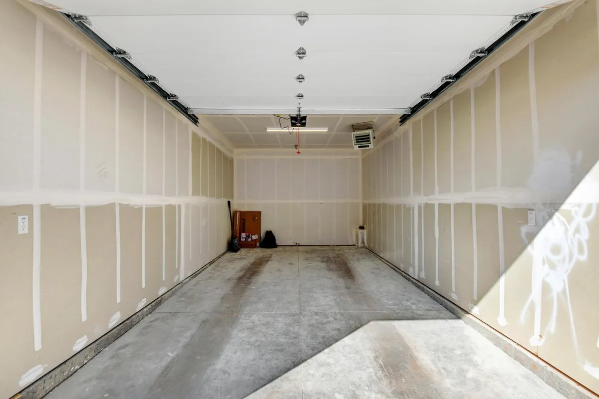 This interior shot captures the condo's garage, with clean concrete floors, bare walls, and a garage door opener. The uncluttered space highlights vehicle storage and potential usability for gear stowage, reflecting the practical perks offered to guests, such as garage parking and storage for adventure equipment.