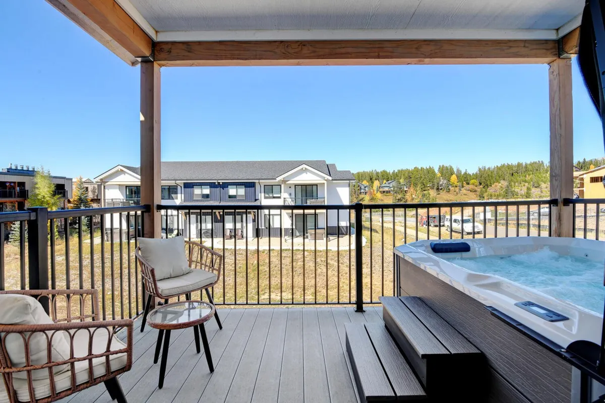 This exterior image highlights a private hot tub and outdoor seating area on a scenic patio, with tranquil views of the surrounding landscape. The hot tub is positioned for relaxation, while the adjacent seating area suggests opportunities for al fresco gatherings and leisurely mornings.