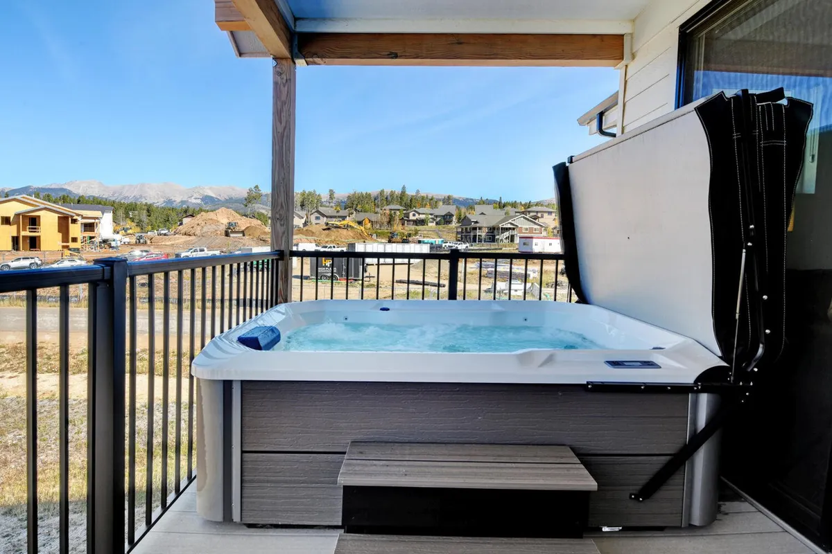 A tranquil balcony hot tub overlooking the mountains. The space invites relaxation and socializing, especially after an active day, with the promise of stargazing or enjoying peaceful views morning and night.